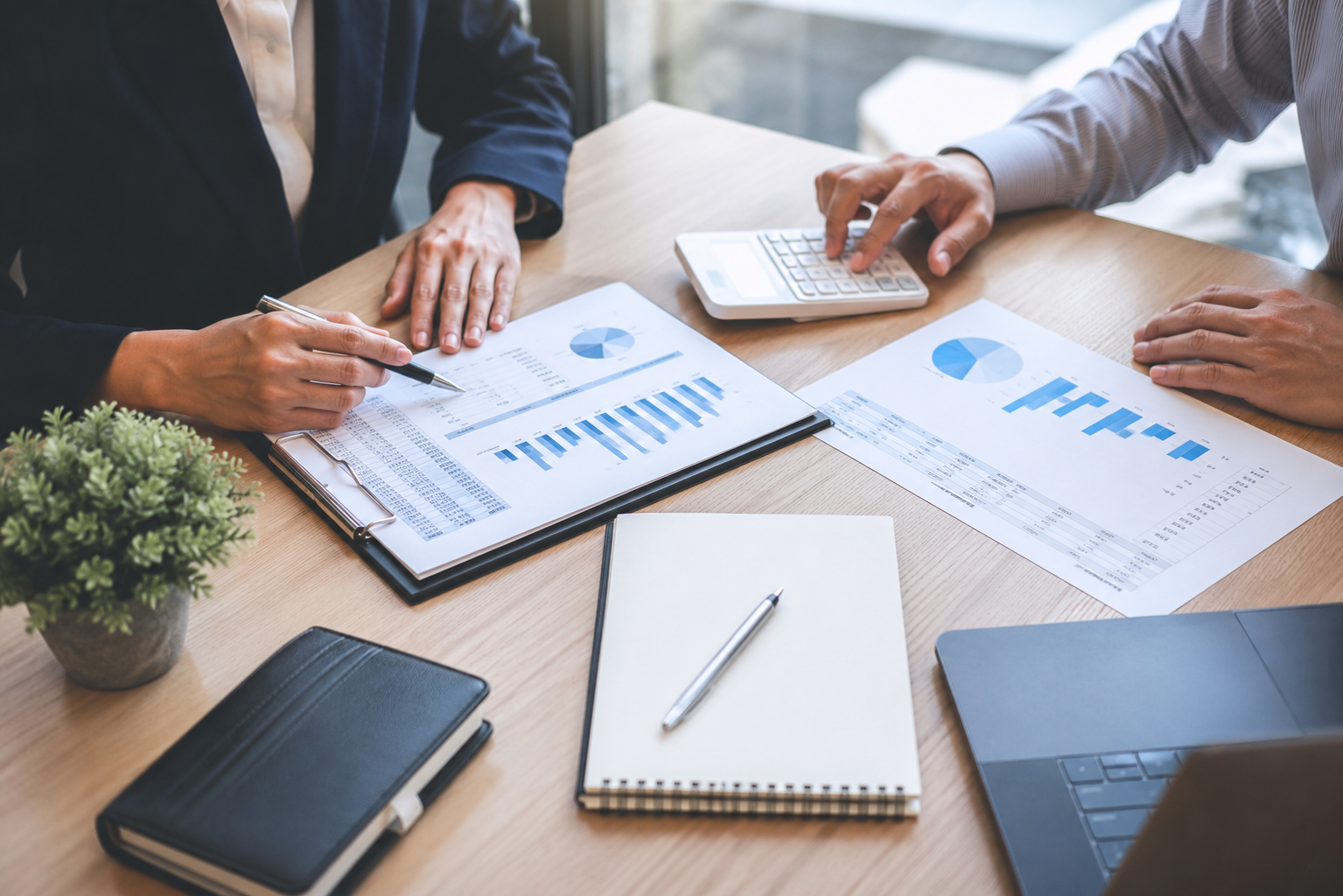 Colleagues reviewing financial charts and calculating figures at a meeting table